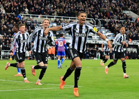 Malick Thiaw wheels away in celebration after scoring, surrounded by his jubilant Newcastle teammates