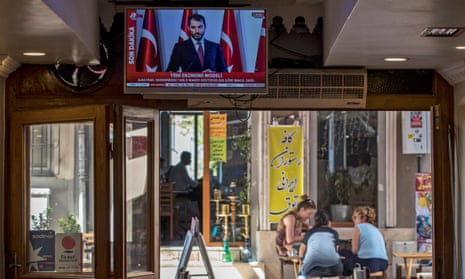 Turkish finance minister, Berat Albayrak, speaks on TV while people drink tea in Istanbul