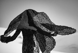 A standing figure draped in a black brocade fabric