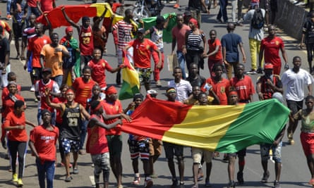 Protesters take to the street in Conakry while carrying the Guinean national flag.