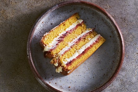 A slice of four-layer sponge cake filled with cream and rhubarb jam.