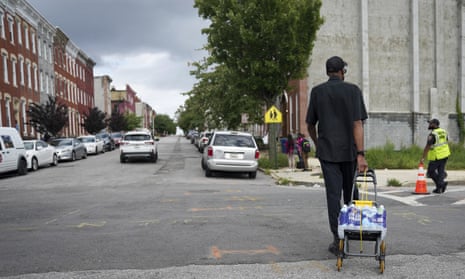 A resident carries bottled water to his home in Baltimore on Tuesday.