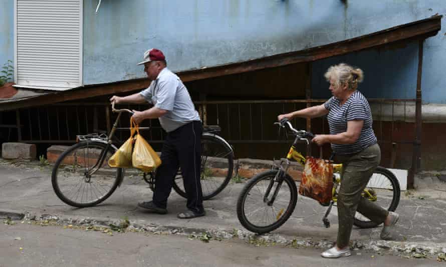 A couple walks bicycles to receive humanitarian aid in Kramatorsk.