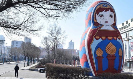 A man walks past a giant statue of a Russian Matryoshka doll on a street in Suifenhe