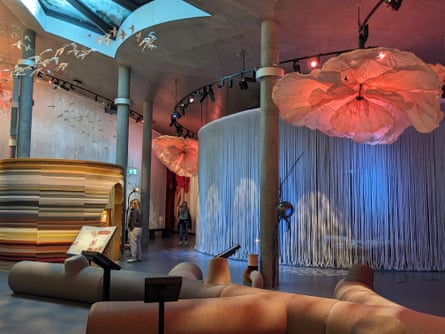 Inside a fantastical-looking museum space with birds and giant flowers suspended from the ceiling