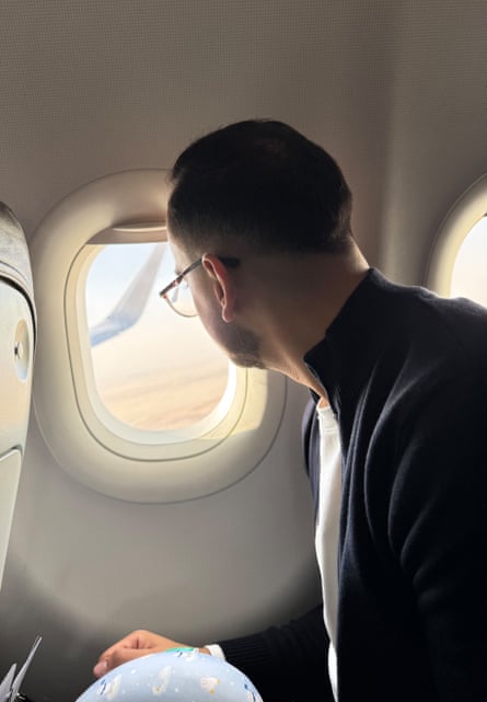 A young man looks out of the window of an aeroplane.