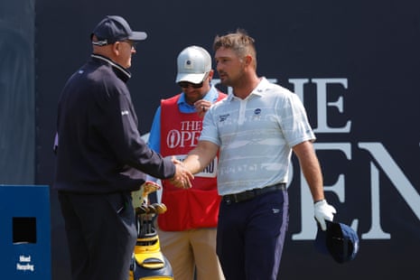 Bryson DeChambeau shakes hands with a rules official.