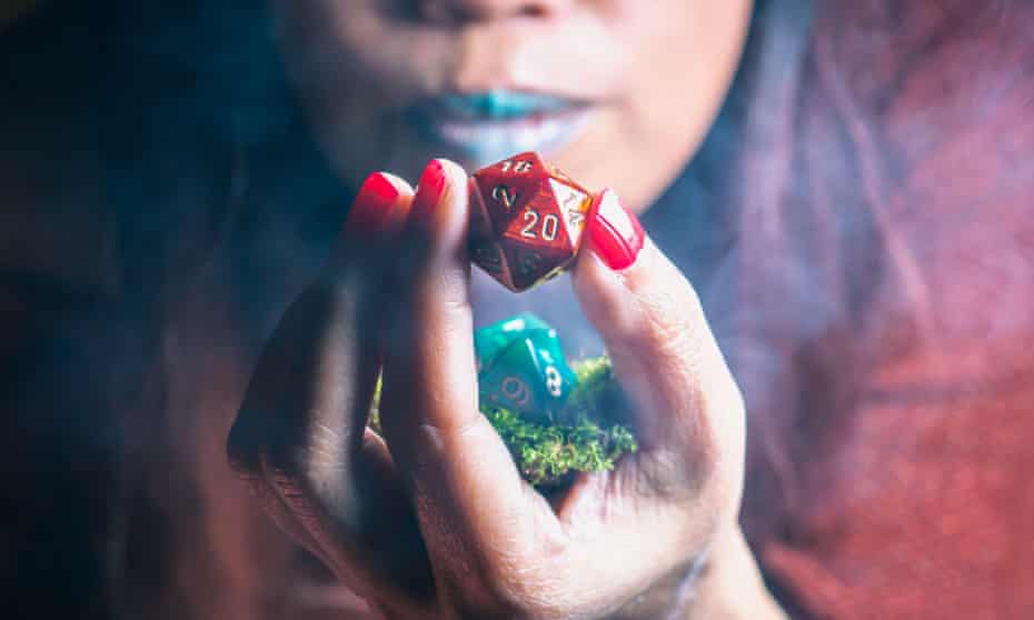 Image of a red 20-sided die held by a woman of colour blowing onto it for good luck