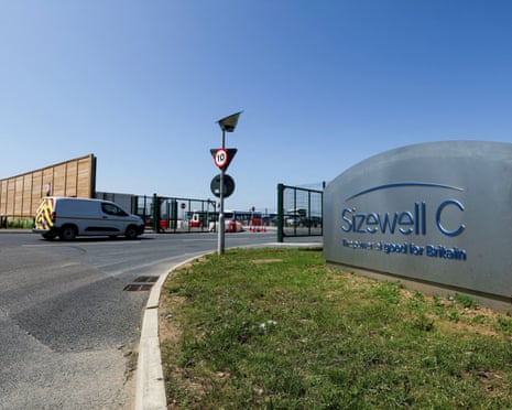 A curved sign reading 'Sizewell C' sits beside a road with traffic signs and a construction site entrance