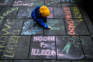 A idiosyncratic writes connected the pavement successful chalk during a protestation against the Polish government’s attraction of refugees successful Kraków