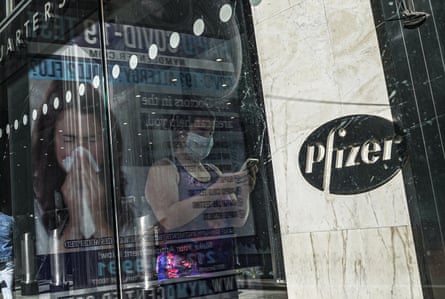In this Nov. 9, 2020, file photo, an ad for COVID-19 testing reflects on glass at a bus stop, as pedestrians walk past Pfizer world headquarters in New York. Pfizer and BioNTech say they’ve won permission Wednesday, Dec. 2, 2020, for emergency use of their COVID-19 vaccine in Britain, the world’s first coronavirus shot that’s backed by rigorous science -- and a major step toward eventually ending the pandemic.