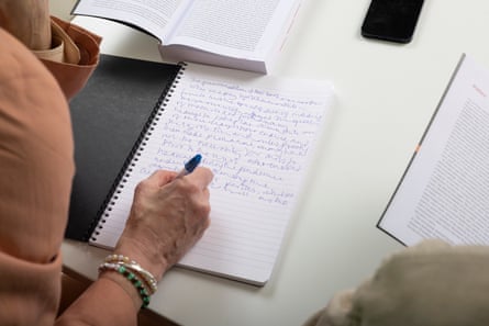 Over-the-shoulder view of Williams writing on to a notepad
