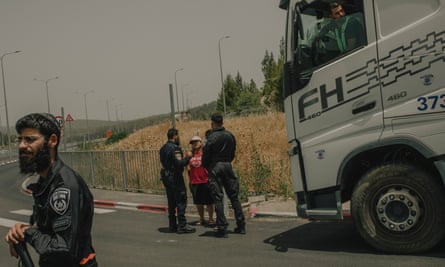 Israeli police officers and settlers stand near a lorry.