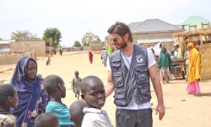 A man in a vest meets children in Nigeria