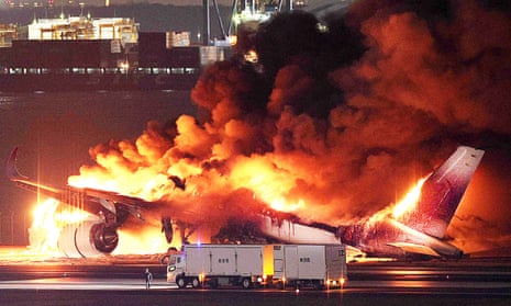 A Japan Airlines plane on fire on a runway of Tokyo's Haneda Airport after colliding with a coast guard aircraft