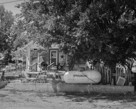 black and white photo of a white wooden house with a propane tank in front