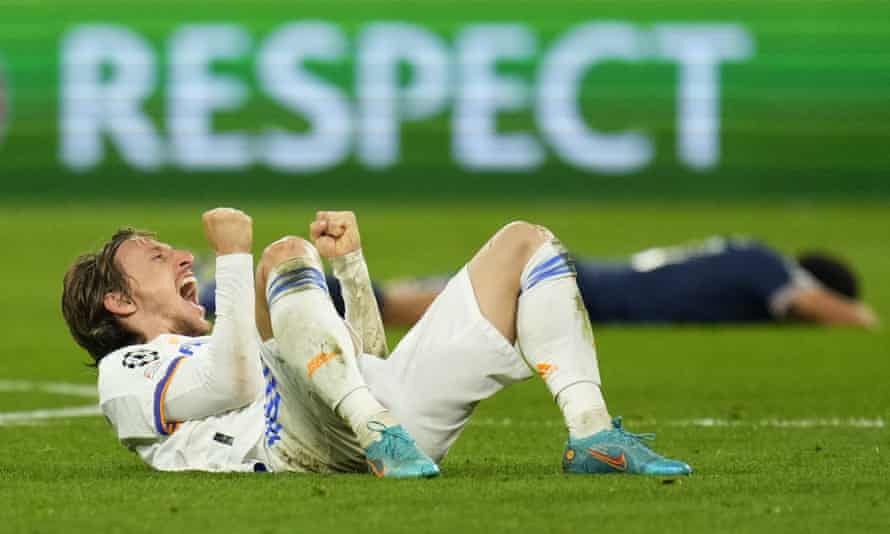 Real Madrid’s Luka Modric celebrates his team’s win as a defeated PSG player lies on the pitch.