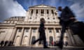 silhouetted figures pass the Bank of England under a bright blue sky
