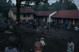 Dozens of war-displaced people stand in the courtyard of an elementary school where they have taken refuge in Minova, DRC