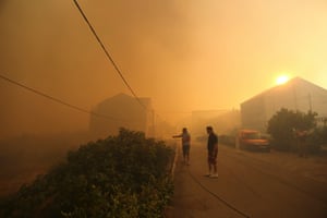 Local residents stand amid smoke as they leave their homes due to a wildfire in the village of Mravinc near Split, Croatia