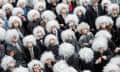 A large crowd of people in suits and grey Einstein wigs