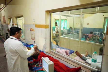 A doctor stands over patient at hospital ward