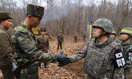 North and South Korean soldiers shake hands during an operation to reconnect a road across the military demarcation line inside the demilitarised zone. 