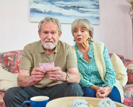 An older couple on a sofa gaze at lottery tickets in disbelief