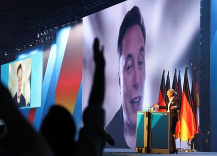 Weidel stands at a lectern with Musk on screen behind her