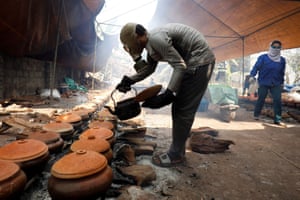 Bui Van Cuong wears a gas mask as he braises black carp in clay pots in Ha Nam, Vietnam