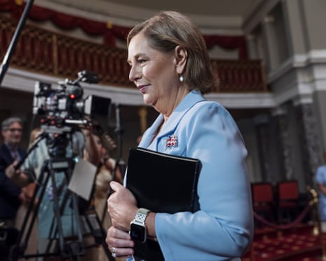 a woman in a blue jacket holds a folio of documents