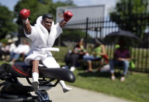 A Muhammad Ali action figure sits on the seat of a bicycle as fans wait for the funeral procession