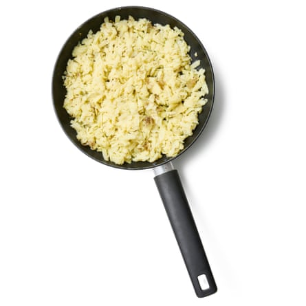Felicity Cloake potato rosti 06a. 6 Разтопете мазнината, след това добавете картофите. Сложете тигана на средно силен котлон, докато мазнината зацвърчи, след което добавете нишките картофи. Бързо ги разпределете, за да напълните тигана, след което гответе необезпокоявани за няколко минути. С помощта на шпатула оформете картофената смес на плоска торта, като я натискате възможно най-леко, за да не смачкате картофите на каша.