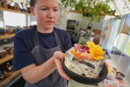A woman carries a dish containing an intricate display of flower petals in a hollowed-out ice block