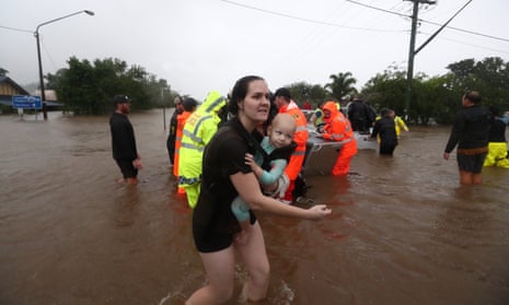 A woman and baby flee flooding in Lismore, New South Wales, Australia