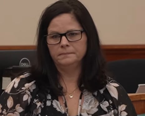 Rhonda Jewell, wearing glasses and a floral top, sits with a serious expression in a courtroom