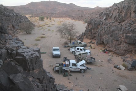 Pickup trucks parked in a rocky, sandy valley