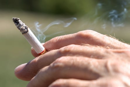 A hand holding a half-smoked cigarette