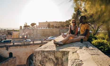 Man and woman enjoy weekend activities, sitting on the walls of the fortress, enjoying the view and casually chatting