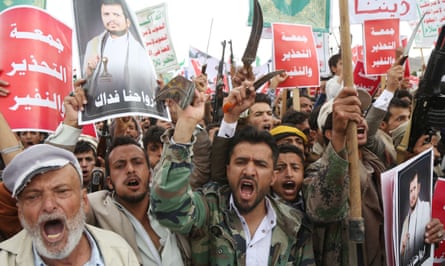 Protesters in Sana’a hold placards and brandish weapons during a protest against Saudi Arabian military siege in northern Yemen.