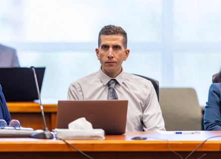 man in button-down and tie sits at table and looks ahead