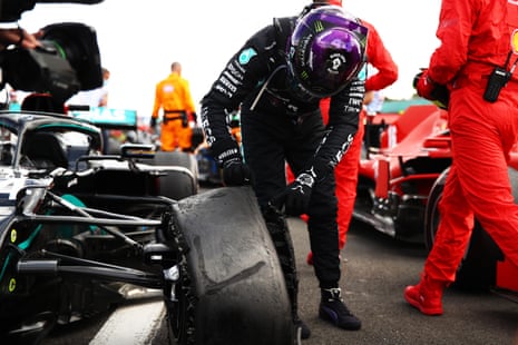 Hamilton inspects his punctured tyre in parc ferme.