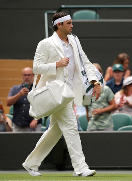 Fritz in white suit with headband carrying bag