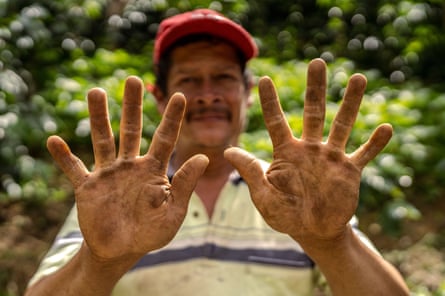 A man hold up his hands, which are covered in mud, to the camera.