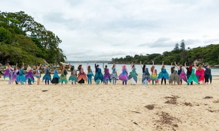 A number of women with mermaid tails standing on a beach