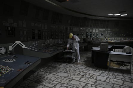 A worker in a white suit and yellow hat in the control room of the defunct Chornobyl nuclear plant on 9 April.