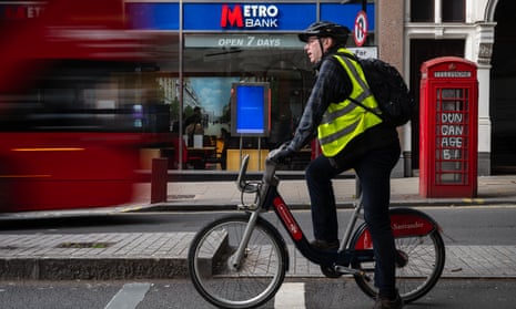 A cyclist and a bus move past a branch of Metro Bank