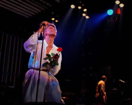 Bowie clutching a single red rose and making an impassioned face while performing on the Isolar II tour