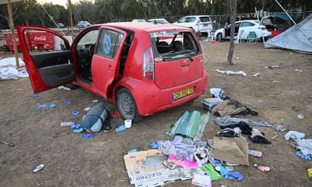 rear view of small red hatchback with rear windscreen shot out and belongings strewn about in foreground