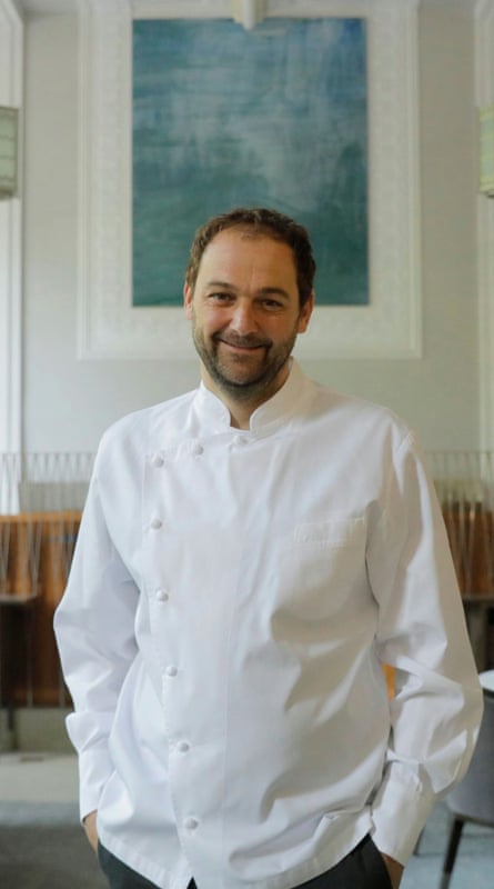 Daniel Humm standing in EMP, with a blue abstract picture behind him